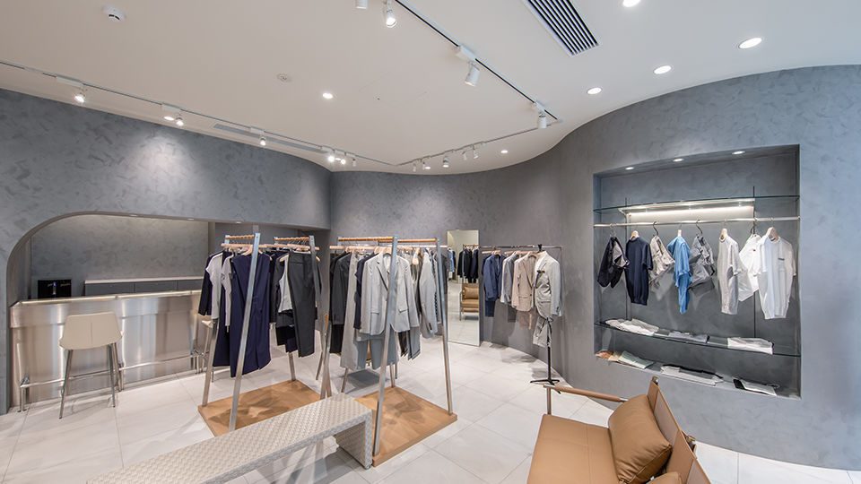 The showroom is a bright and stylish space. The wall is painted silver with textured brush strokes, and the curves resembling a body line, creating a soft nuance. The wood materials add warmth.