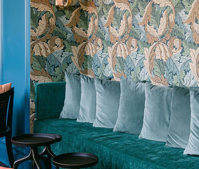 The sitting nook features Art Nouveau style wallpaper, Art Deco vintage peacock sconces and custom upholstery.