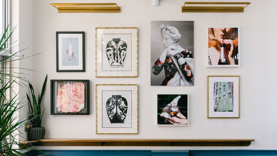 Designers Jaclyn Journey and Amanda Jacobs curated a gallery wall with a selection of art from various places, including well-known artists from Paris and another from Los Angeles. A portion of original wallpaper from the building when the owners bought it was framed in a shadow box.