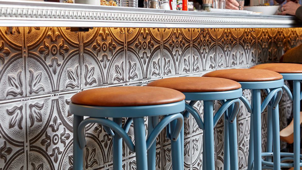 Decorative tin ceiling tiles are used as the face of the bar front, providing texture and continuing the language of decorative utilitarianism. The zinc bar top with decorative edge detailing is a nod to the decorative nature of materials found throughout the Capitol Hill area.