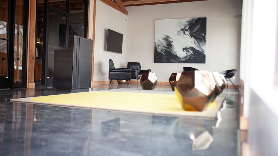 The designers created a custom geometric wool carpet to adorn the waiting area. The ceramic stools are finished in a crackled gold. The unique seating is suitable for both indoor and outdoor use. Additional seating also includes two black high gloss finish hammered metal chairs, and embossed leather arm chairs. The design goal for this waiting room was to maintain the overall minimal and industrial feel of the existing building with an emphasis on luxury details.