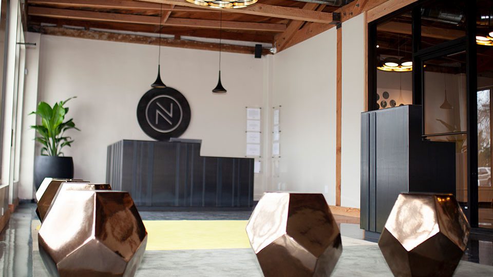 The reception area showcases three custom metal work pieces created by San Francisco metal sculptor Kevin Craford—the NUG logo, reception desk and security podium. Hot, rolled steal with a patina finish for the outside of the desk and a meticulously crafted walnut interior, the same design is mirrored on the reception podium. The logo is laser jet cut and finished similarly. The use of the negative space in the logo design allows for the logo to appear so prominent against the wall without any additional illumination.