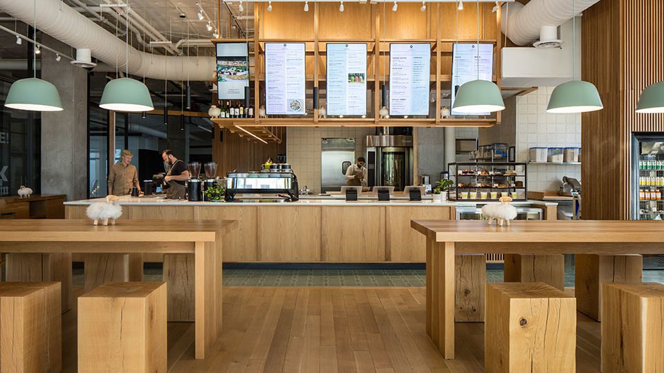 The soft graining of the tongue-and-groove solid white oak wood flooring represents the land [landskap]. On top of the flooring rests the solid white oak timber furniture, which appear like an organized arrangement of Swedish toy blocks. Each custom-designed furniture piece is playful and heavy, yet smooth to the touch. The massive wood shelving, suspended over the entire length of the L-shaped coffee bar, represents the lattice of the tree canopy. The open shelving serves as a focal point used for menu and merchandise display.