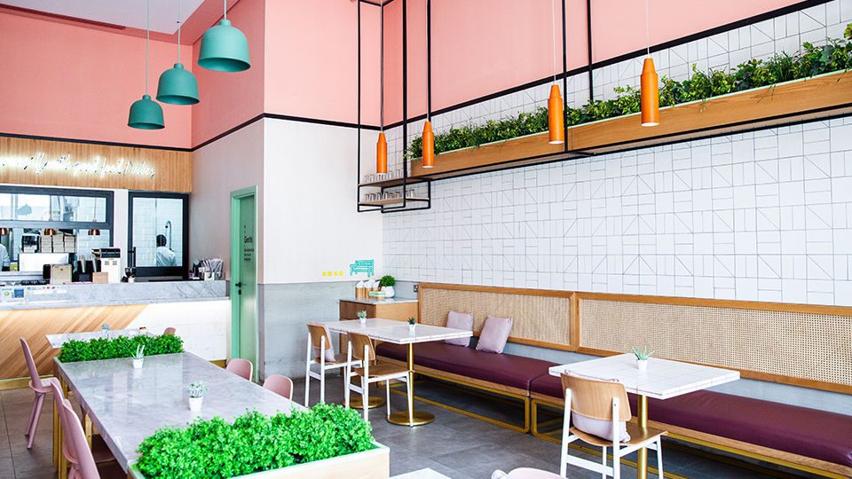 The color pink gives the space its bold identity, while the timber and rattan materials help to ground the space. The colors in the furniture portray a fresh feeling with variations of pinks and greens to reflect the branding.