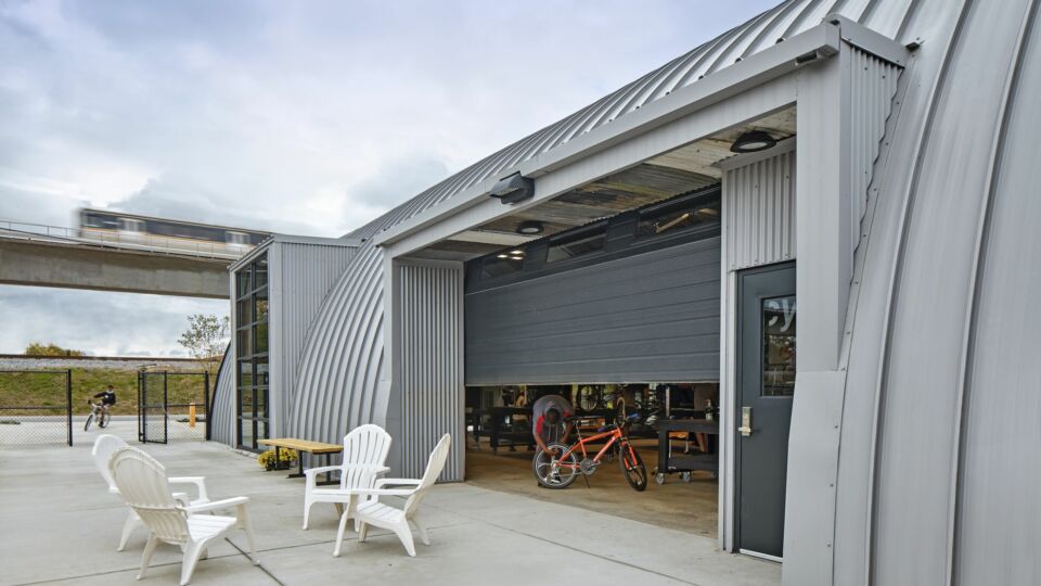 Part of the renovation will include preserving the building where the nonprofit is located. It was important for the NELSON Worldwide team to maintain some of the two structures’ standout-qualities. Arched metal ceilings and walls were integrated into the design, and existing garage doors allow natural light to flow through the interiors and provide employees and students with a visual connection to their surroundings.