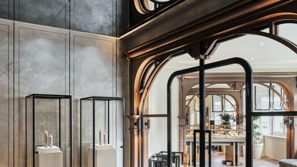 A private room, situated to the right of the main room and accessed via floor-to-ceiling glass doors, is where Melis Göral showcases its diamond collection in elegant glass cabinets. Here the flooring changes to wall-to-wall carpet in gray, and the ceiling is covered with mirrored glass to make the room’s interior feel more spacious.