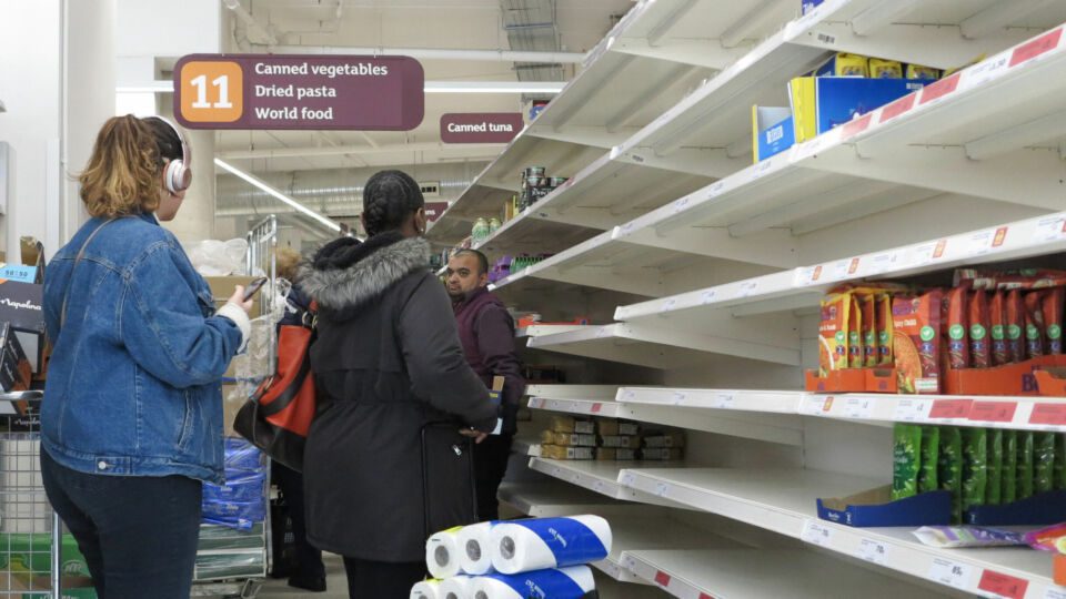 Group of shoppers in store aisle with empty shelves