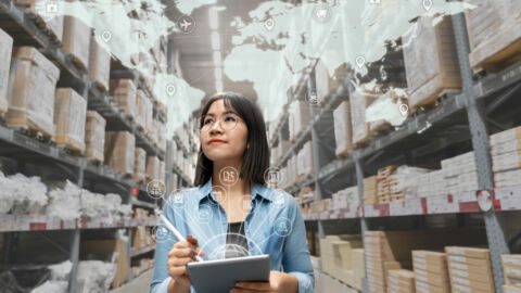 Woman walking through a warehouse taking inventory using a tablet