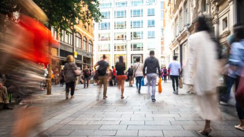 Large group of people walking down a busy street, blurred by speed