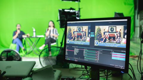 Two people in front of a green screen in a recording studio hosting a livestream