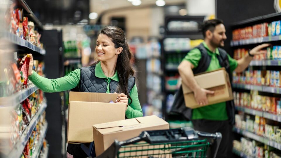 Two associates in a grocery store, engaged with their work and stocking shelves.