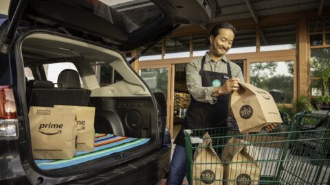 Whole Foods worker loads a car with a grocery delivery.