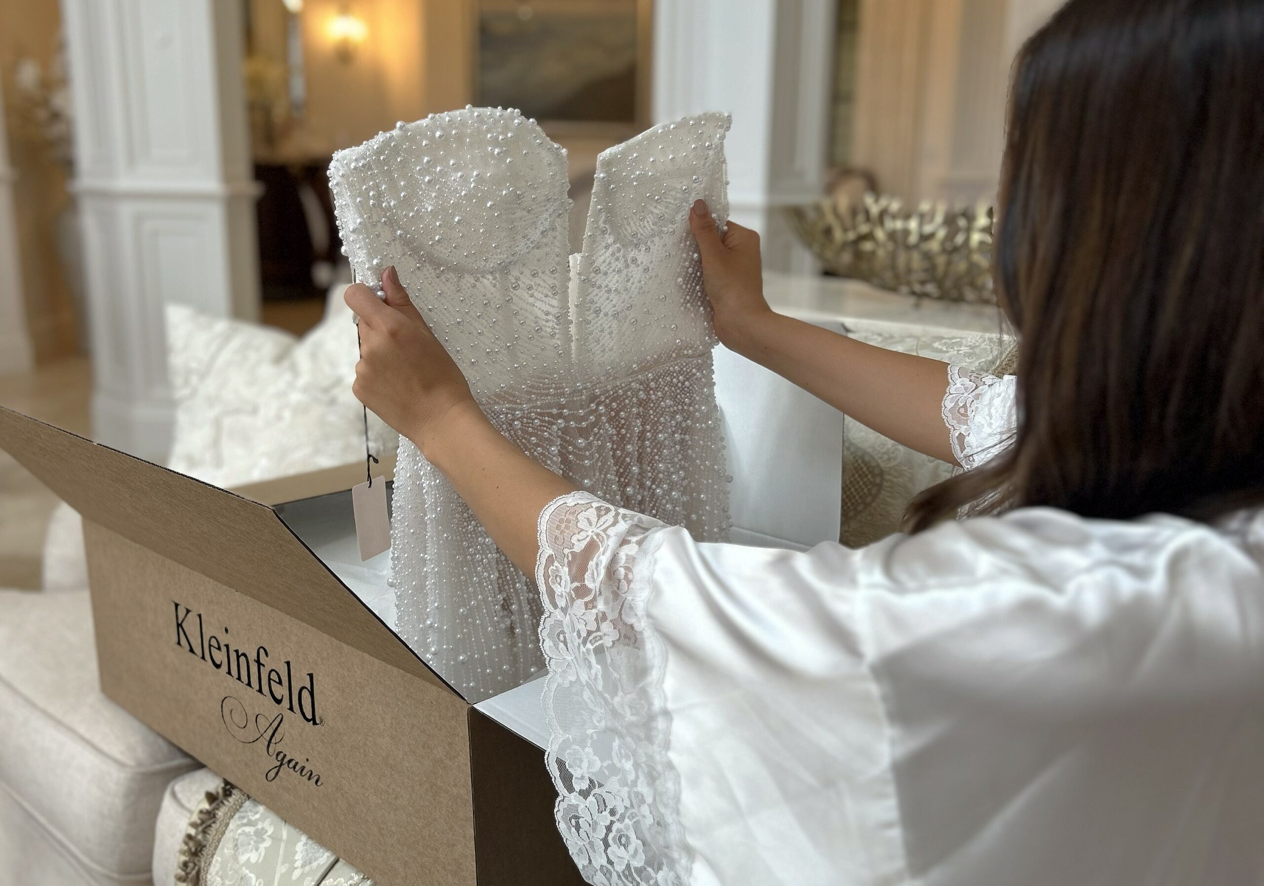 A bride admires her new pre-owned dress from Kleinfeld Again.