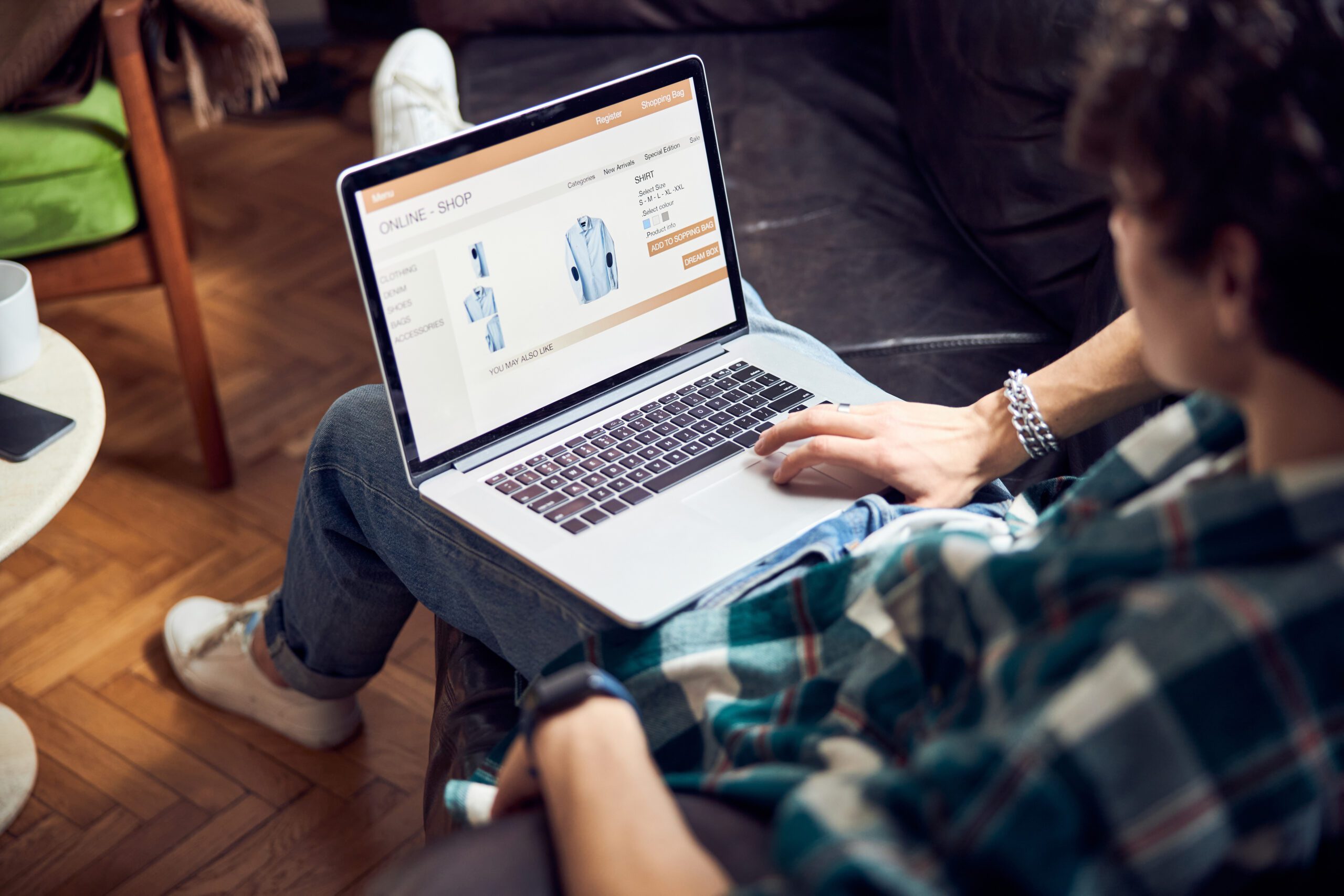 Close up of guy with laptop on his laps buying shirt in online shop stock photo